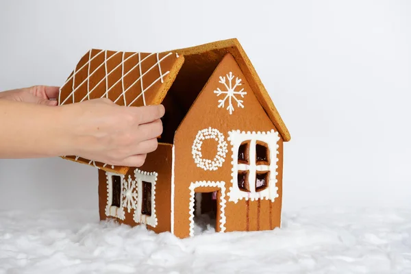 A casa de gengibre comestível feita à mão, acrescentando pela mão de parte da decoração de telhado e neve — Fotografia de Stock
