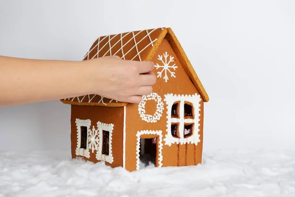 A casa de gengibre comestível feita à mão, acrescentando pela mão de parte da decoração de telhado e neve — Fotografia de Stock