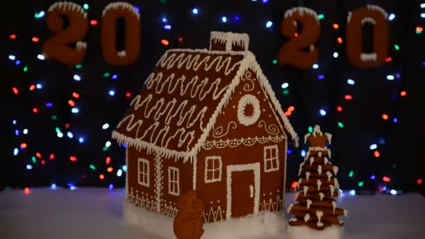 手作りの食べられるジンジャーブレッドハウス マウス 2020年のシンボル 新年の木 2020年の碑文 雪の装飾 花輪の背景照明 — ストック動画