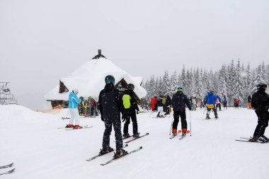Bukovel, Ukrayna - 25 Aralık: Filvarok restoranının ahşap binası ve kayakçılar Bukovel kayak merkezinin yamacında bulunmaktadır. 25 Aralık 2018 tarihinde Bukovel, Ukrayna 'da 68 km pisti bulunan Ukrayna' nın en büyük kayak merkezidir.
