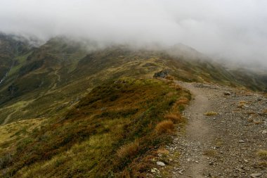 Dağ bulutlarında yağmurlu bir gün ve yol üzerinde yeşil tepeler