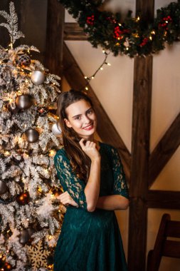 Güzel Noel ağacı evde yakınındaki bir hediye kutusu ile gülümseyen genç kız. Lüks Noel dekorasyonu. Noel ve yeni yıl hediye.