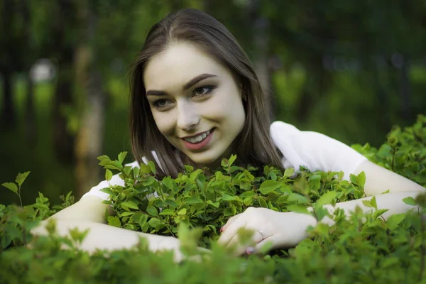 Portrait of a beautiful young woman on a background of green leaves, summer outdoors. — Stock Photo, Image