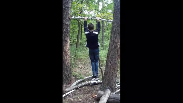 Мальчик Подтягивается Горизонтальной Полосе Лесу — стоковое видео