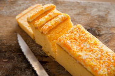 Dilimlenmiş taze vanilyalı kek kremalı ve ahşap bir masada tırtıklı mutfak bıçağı.