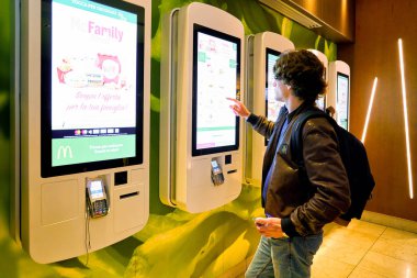 MILAN, ITALY - CIRCA NOVEMBER, 2017: customer at a McDonald's store place orders and pay through self ordering kiosk. clipart