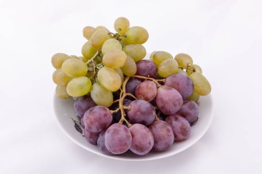 bir plaka üzerinde mor ve yeşil üzüm demet