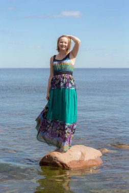 Denizde bir taş üzerinde uzun elbiseli kız