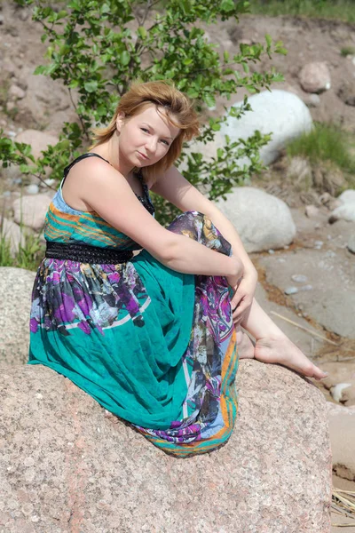 石の上に座っている明るいドレスの女の子 — ストック写真