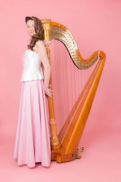 一个女孩的肖像与竖琴在粉红色的背景 — 图库照片