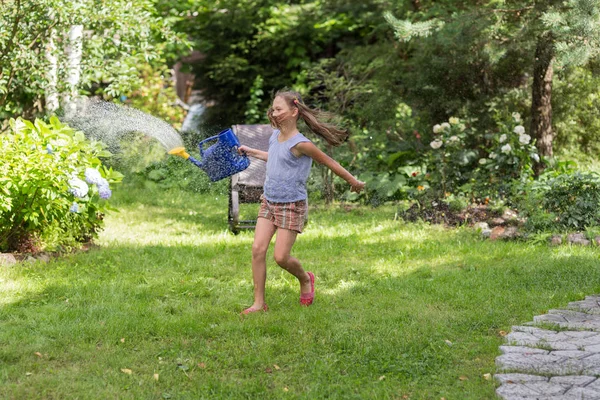 Girl with a watering can in the summer — Stock Photo, Image