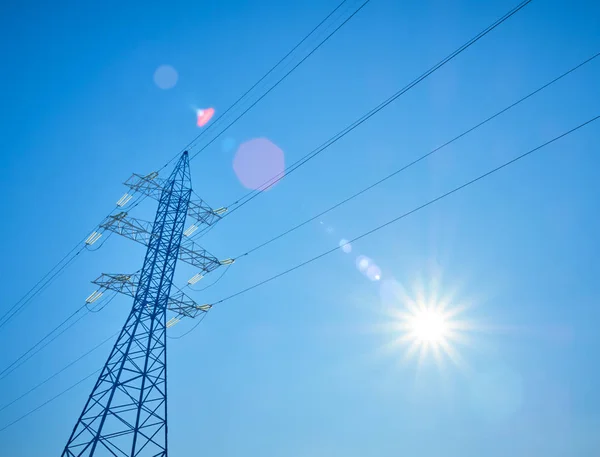 太陽と青空を背景に高圧送電線 — ストック写真