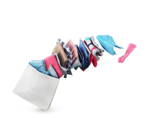 La ropa está volando desde la bolsa de papel sobre un fondo blanco — Foto de Stock