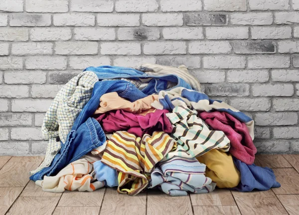 Pilha de roupas no chão perto da parede de tijolo — Fotografia de Stock