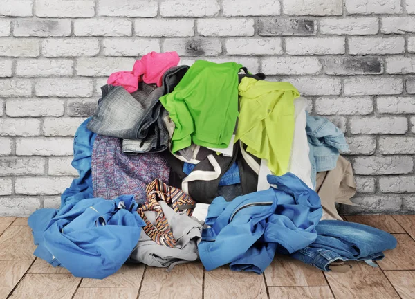 Stapel van kleren op verdieping in de buurt van bakstenen muur — Stockfoto