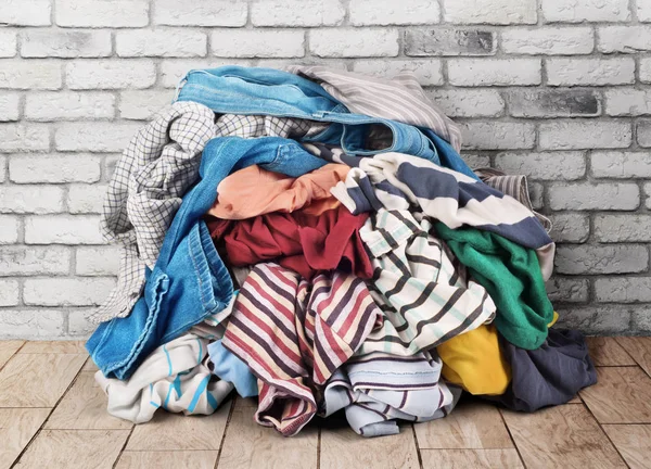 Pilha de roupas no chão perto da parede de tijolo — Fotografia de Stock