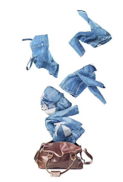 Jeans-Klamotten fliegen aus der Gepäcktasche — Stockfoto