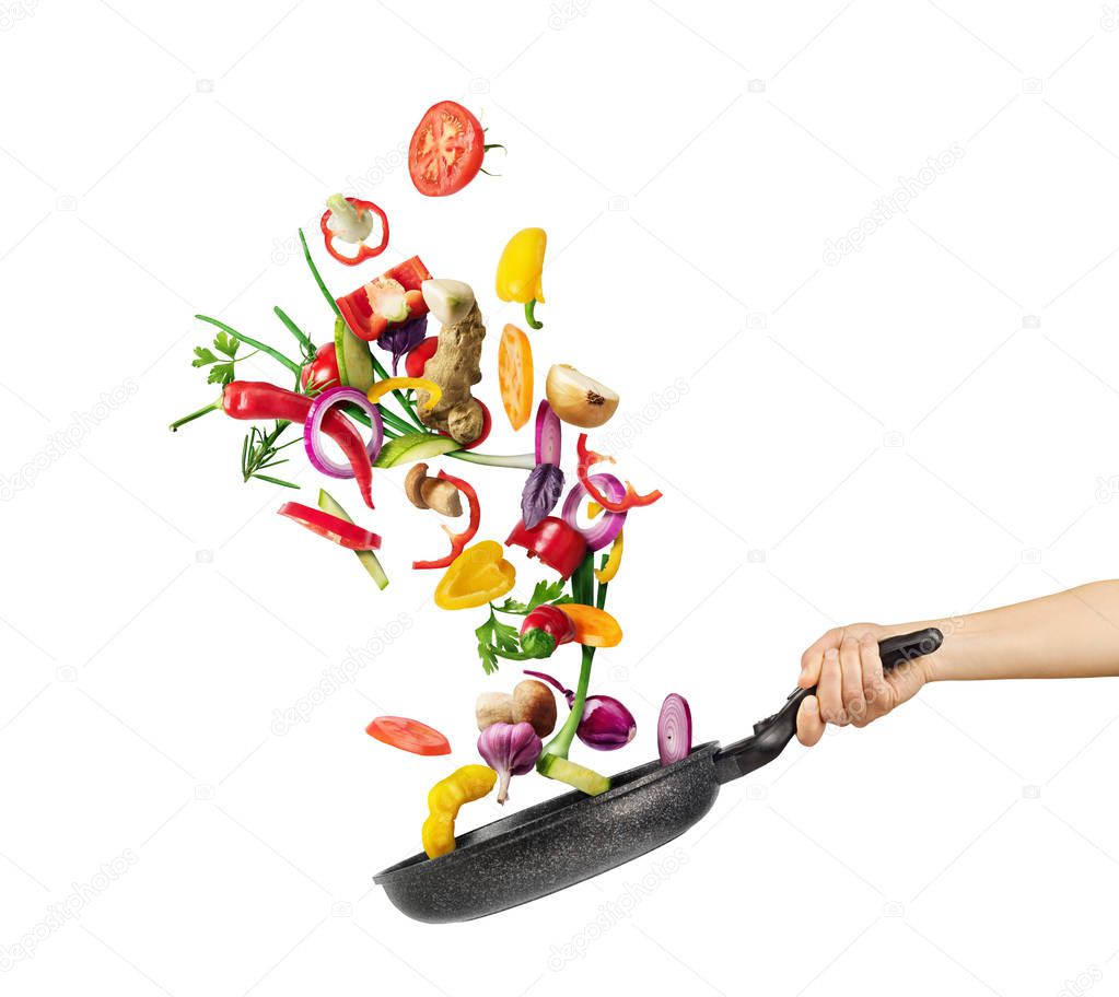Cooking concept. Vegetables are flying out of the pan isolated o