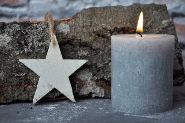 Beton üzerinde yanan mum, yıldız ve ahşap kütük