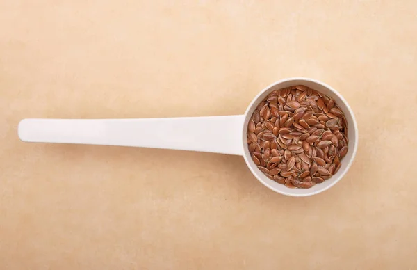 Linseed in measuring spoon on brown background — Stock Photo, Image