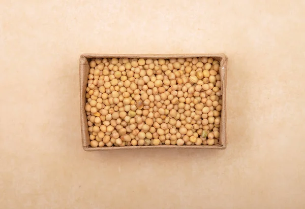 Mustard seeds in carton on brown background — Stock Photo, Image