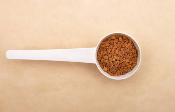 Instant Coffee with measuring spoon on brown background — Stock Photo, Image