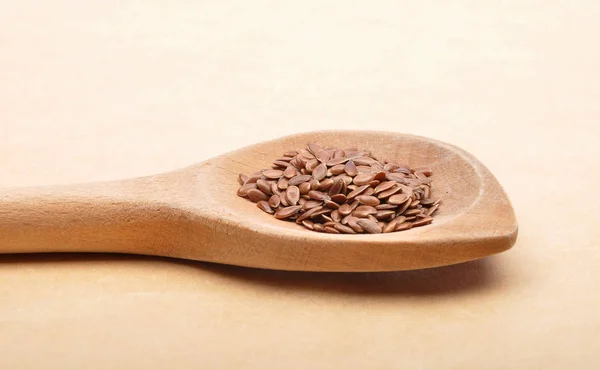Linseed on wooden spoon and brown background — Stock Photo, Image