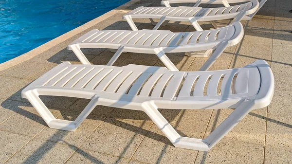 旅游胜地游泳池边的一排免费的日光浴床 图库照片