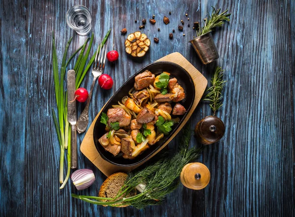 Сковородка с нарезанной жареной свининой и овощами на деревенском деревянном пакете — стоковое фото