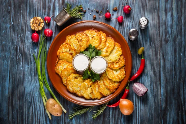 Potato pancakes with sour cream and dill on wooden background. — Stock Photo, Image