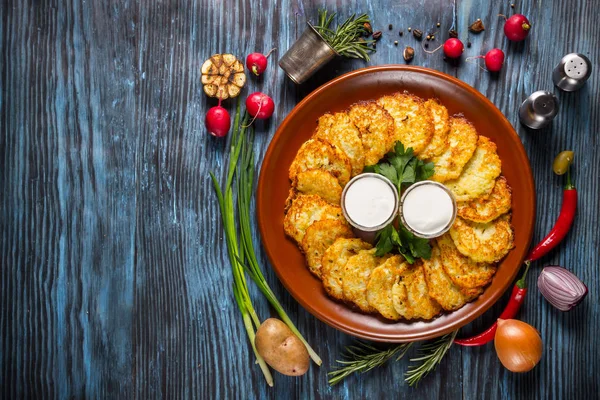 Potato pancakes with sour cream and dill on wooden background. — Stock Photo, Image