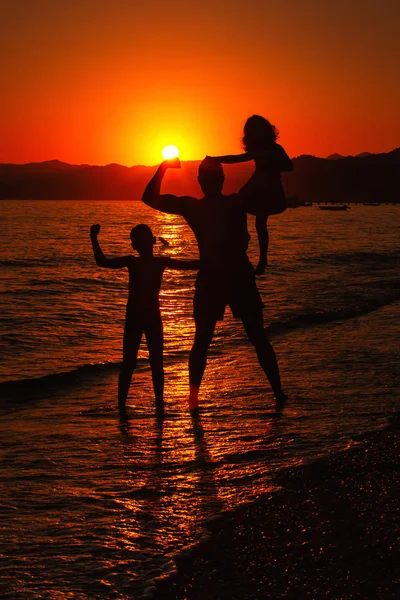 Щасливі сімейні силуети над заходом сонця — стокове фото
