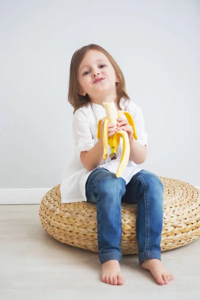 白い背景の上にバナナを食べて満足しているかわいい女の子の肖像画 — ストック写真
