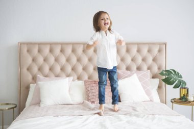 Mutlu küçük şirin kız eğleniyor yatağa atlama portresi