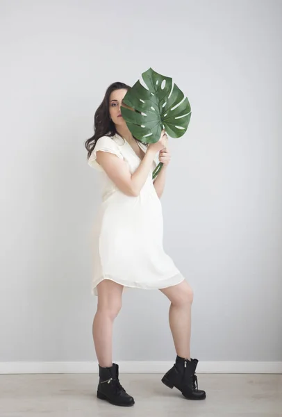 Brunett Gravid Kvinna Som Bär Vit Klänning Holding Monstera Blad — Stockfoto