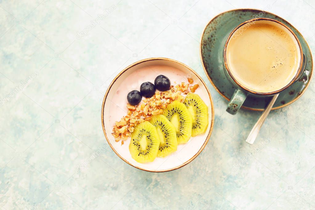 Cup of granola with yogurt and fruit on turquoise background