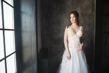 Pencerenin yakınındaki koyu arka plan üzerinde güzel genç kadın portresi