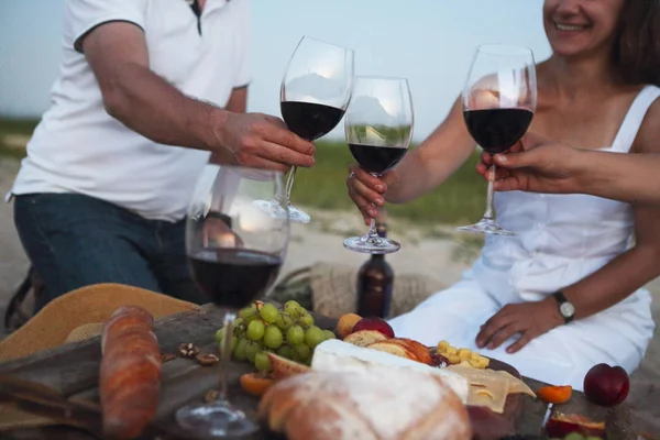 People drinking red wine outdoor. Summer picnic on the beach