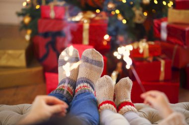 Noel arka plan üzerinde Bengal ışıkları ile mutlu bir aile. Anne ve kızı Noel ağacı tarafından