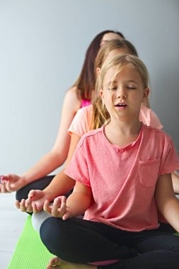 Genç kadın yoga yaparken çocuklarla eğleniyor. Aile spor kavramı