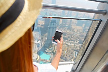 Uluslararası Dubai Kongre ve Sergi Sarayı, Dubai, Birleşik Arap Emirlikleri, BAE gökdelen pencere tarafından cep telefonuyla kız turist. Yakın çekim