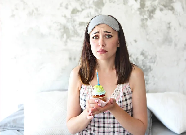 Sad lonely woman on her Birthday holding cupcake in her bedroom