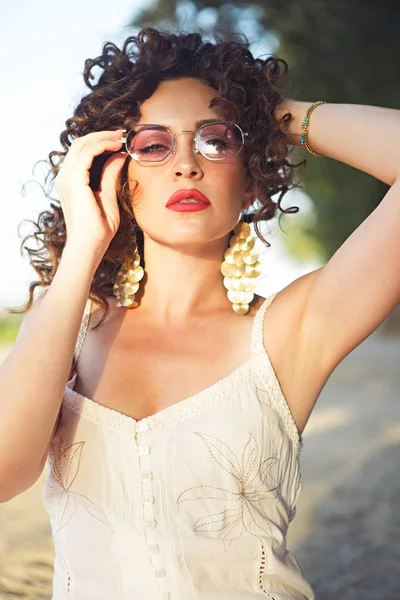 Party girl at summer festival wearing pink sunglasses and golden earrings