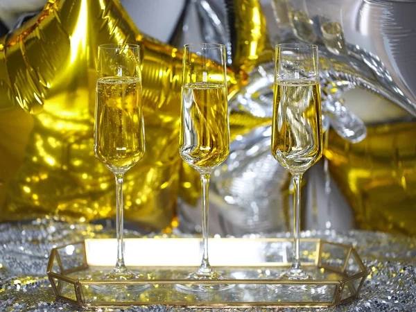 关闭闪亮的香槟杯在黑色 金色和银色气球背景 — 图库照片