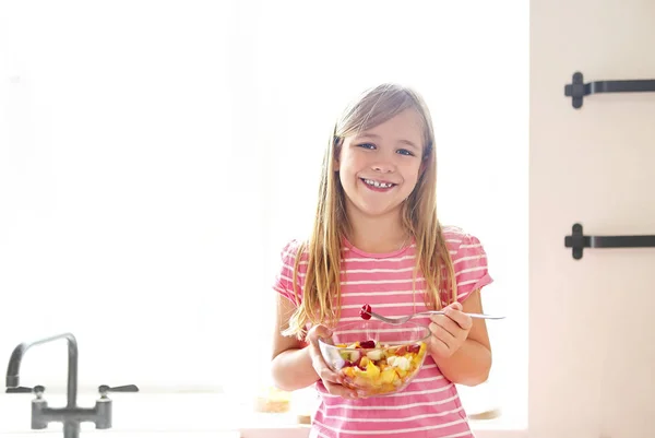 キッチンに新鮮なフルーツ サラダを食べて かわいい女の子の肖像画 — ストック写真