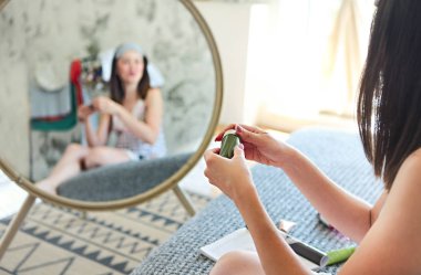 Sevimli gülümseyen kadın yatak odasında sabah krem uygulamak. Yakın çekim