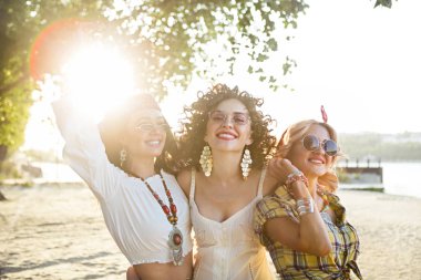 Happy slim tan women are dancing on the beach in sunset. Travel and happiness concept