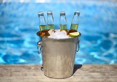 Buz küpleri, bira şişeleri ve havuz kenarında kireç dilimleri ile kova closeup görünümü