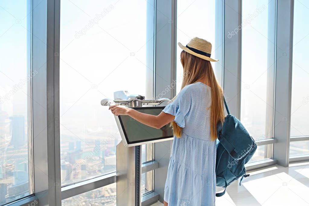 Girl tourist by the window of skyscraper of the Burj Khalifa in Dubai, United Arab Emirates, UAE