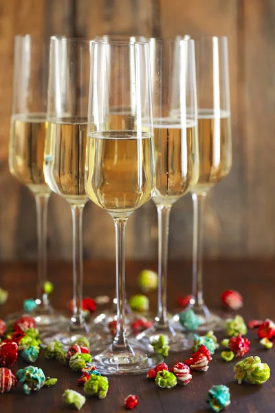 Glasses of champagne with pop corn on wooden background